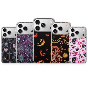Peut inclure: Cinq coques de smartphone transparentes avec divers motifs d'horreur : crânes avec croix et nœuds roses, toiles d'araignée avec chauves-souris, visages de citrouilles orange, une poupée Chucky style néon et des cœurs roses avec des couteaux.