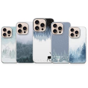 May include: Five clear phone cases featuring winter landscape designs. The patterns include snowy mountain ranges, dense pine forests in shades of blue and grey, falling snowflakes, and a silhouette of a deer standing in a snowy field.