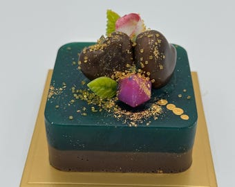 Schokoladen-Smaragd-Käsekuchen mit Schokoladenherzen, Edelsteinen und Rosenblüte.