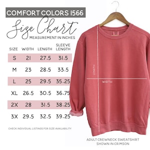 May include: Crimson adult crewneck sweatshirt on a wooden hanger. The image includes a size chart with measurements in inches for width, length, and sleeve length. The size chart is for Comfort Colors 1566 sweatshirts.
