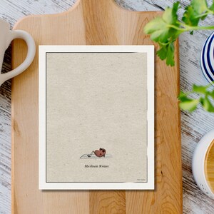 K&ouml;nnte beinhalten: Eine braune Kaffeebohne, die Yoga auf einer wei&szlig;en Matte macht, mit dem Text "Medium Roast" darunter. Das Bild ist auf einem beigefarbenen Hintergrund.