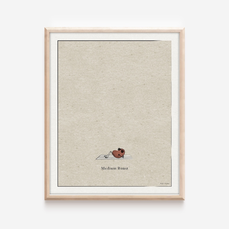 K&ouml;nnte beinhalten: Eine gerahmte Illustration eines Kaffeekorns, das auf dem R&uuml;cken liegt und die Beine in die Luft streckt. Das Korn ist braun und hat einen kleinen wei&szlig;en Kreis auf dem Kopf. Der Text "Medium Roast" befindet sich unter dem Korn. Der Hintergrund ist hellbeige.