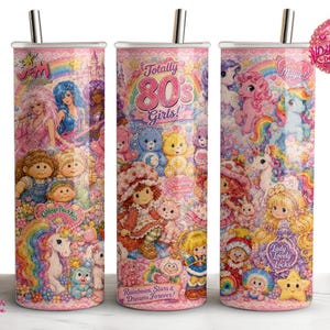May include: Three cylindrical tumblers with metal straws featuring a colourful 1980s-themed collage. Graphics include cartoon characters, unicorns, rainbows, and text such as Totally 80s Girls, Cabbage Patch Kids, Strawberry Shortcake, and Lady Lovely Locks.