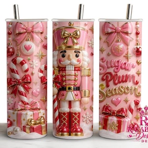 Puede incluir: Tres vasos cilíndricos con pajitas de metal con temática navideña en rosa y rojo. Los diseños incluyen un cascanueces, bastones de caramelo, regalos, lazos y adornos. El texto Sugar Plum Season está impreso en una fuente 3D dorada y rosa.