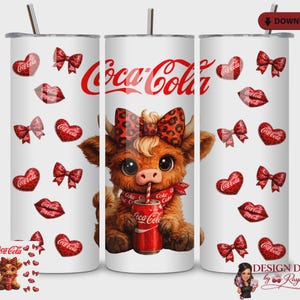 May include: A white tumbler featuring a cartoon cow with a leopard print bow, scarf, and a Coca-Cola can. Red hearts, bows, and lips with Coca-Cola branding decorate the tumbler. A silver straw is visible.