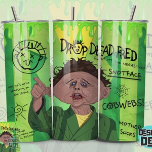 Può includere: Un bicchiere in acciaio inossidabile con un design verde e giallo con il testo "DROP DEAD FRED" e un'immagine a cartoni animati di un uomo. Il bicchiere ha anche le parole "SNOTFACE" e "COBWEBS!"