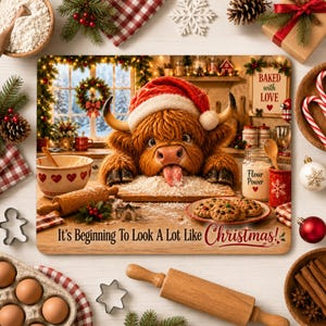 May include: A rectangular cutting board featuring a fluffy Highland cow wearing a Santa hat, with its tongue out on a pile of flour. The board displays the text "It's Beginning To Look A Lot Like Christmas!" and shows cookies, a rolling pin, and jars labelled "Flour Power".