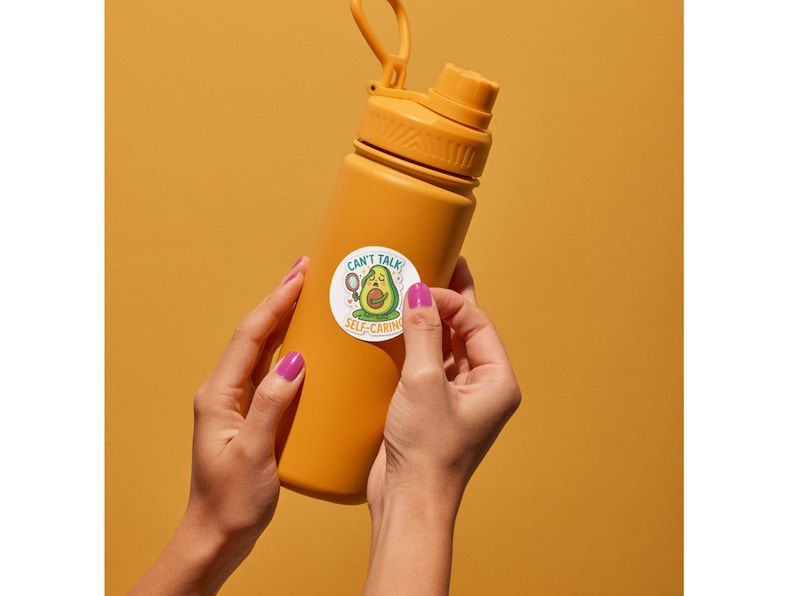 Op de afbeelding: Een matte mosterdgele waterfles met een schroefdop en een draaglus. In het midden is een ronde sticker aangebracht met een cartoon avocado die een gezichtsmasker draagt en een spiegel vasthoudt, met de tekst CAN'T TALK SELF-CARING.