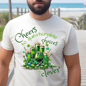 Puede incluir: Camiseta blanca con un gráfico verde que presenta vasos de cerveza verde, tréboles y el texto "Cheers to questionable choices and clover." El diseño tiene un estilo de dibujos animados, perfecto para el Día de San Patricio.