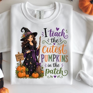 May include: White sweatshirt featuring a witch graphic with the text "I teach the cutest pumpkins in the patch." The witch is wearing a black dress, hat, and holding a broom. Orange pumpkins are at the bottom of the graphic.