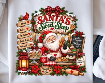 Może przedstawiać: Biała bluza z kolorową grafiką przedstawiającą Świętego Mikołaja w sklepie ze słodyczami. Wzór zawiera napisy Santa's Sweet Shop, Life is Sweeter at Christmas oraz Baked with Love, w otoczeniu ciasteczek, ciast i świątecznych dekoracji.