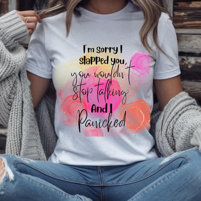 Może przedstawiać: Biała koszulka z napisem "I'm sorry I slapped you, you wouldn't stop talking and I panicked" czcionką w kolorze czarnym. Koszulka posiada kolorowe plamy w stylu akwareli w kolorze r&oacute;żowym, pomarańczowym i ż&oacute;łtym.