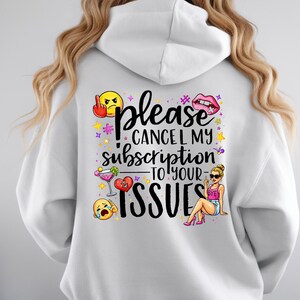 May include: White hoodie featuring a colourful graphic on the back. The design reads "Please Cancel My Subscription To Your Issues" with emoji and illustrations, including a middle finger, lips, and a cocktail.