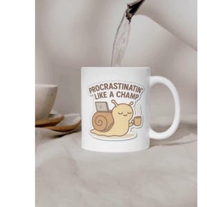 Op de afbeelding: Een witte keramische mok met een cartoonillustratie van een lichtbruine slak met een huisje, die een klein bruin kopje vasthoudt en naast een laptop zit. De tekst boven de slak luidt "PROCRASTINATIN' LIKE A CHAMP" in bruine hoofdletters.