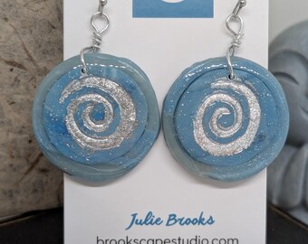 Pendientes colgantes de espiral costera con diseño zen azul y hojas de plata.