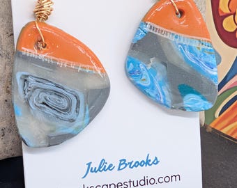 Pendientes colgantes estilo boho con piedras sintéticas naranjas y azules.