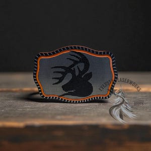 May include: A rectangular patch with a black deer silhouette on a gray mesh background, framed by an orange and black border. The patch has the text "LASERWORKS" and "ROOTS" on the right side.