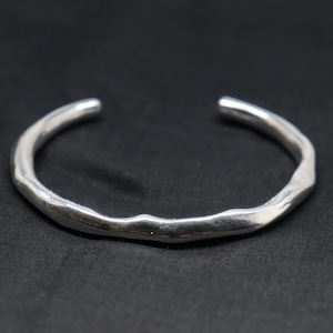 May include: A silver-colored cuff bracelet with an irregular, organic, and wavy surface texture. The bracelet features a polished, reflective finish and an open-ended design, creating a continuous, flowing shape that curves into a circular form.