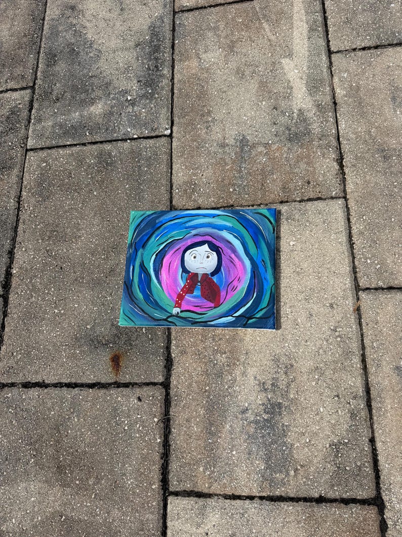 May include: A rectangular painting featuring a cartoon character in a red jacket and black pants, surrounded by swirling blue, teal, and pink colors. The artwork is set against a gray, textured surface.