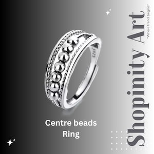 Puede incluir: Anillo plateado con una fila central de pequeñas cuentas redondas. El anillo ajustable se presenta sobre un fondo degradado. El texto "Centre beads Ring" se muestra en la parte inferior.