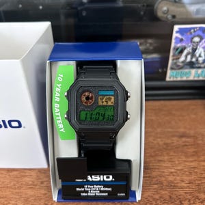 Puede incluir: Reloj digital Casio negro con esfera rectangular, presentado en su caja original. El reloj muestra la hora digitalmente. La caja incluye texto que indica una bater&iacute;a de 10 a&ntilde;os y resistencia al agua.