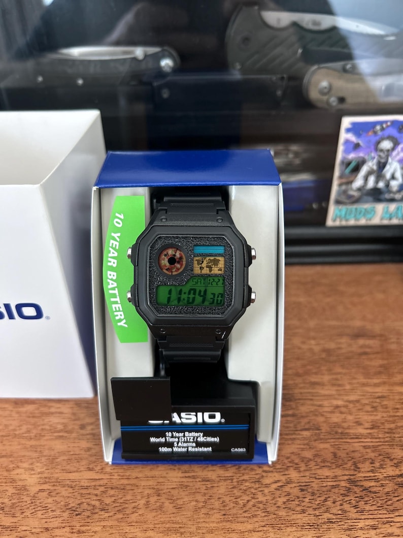 Puede incluir: Reloj digital Casio negro con esfera rectangular, presentado en su caja original. El reloj muestra la hora digitalmente. La caja incluye texto que indica una bater&iacute;a de 10 a&ntilde;os y resistencia al agua.