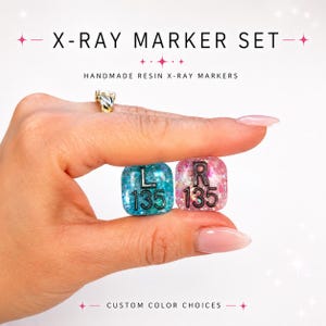 May include: A set of two square resin X-ray markers featuring glittery finishes. One marker is teal with the black letters L and 135, while the other is pink with the black letters R and 135. The text X-RAY MARKER SET, HANDMADE RESIN X-RAY MARKERS, and CUSTOM COLOR CHOICES appear.