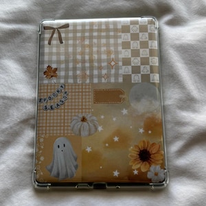Puede incluir: Funda transparente para teléfono con un diseño de collage con un fantasma, una calabaza y un girasol. El diseño incluye un patrón de cuadros beige y blanco, hojas y las palabras "Spooky Season".