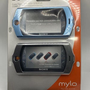 May include: A package containing two Sony mylo communicator color faceplates. One is light blue, the other is dark gray. The package includes the text "Personalize your mylo communicators color" and "mylo my life online."