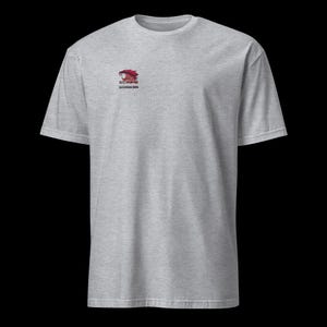 以下が含まれることがあります： 左胸に小さなロゴが入ったヘザーグレーのTシャツ。ロゴは、赤と黒のスタイリッシュなクーガーの頭で、下に「Savage 2004」の文字が入っています。Tシャツは半袖で、クルーネックです。