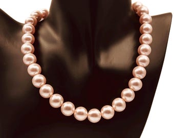 May include: A necklace of pale pink pearls, displayed on a black mannequin bust. The pearls are spherical and uniform in size, forming a classic necklace. The background is plain white, accentuating the jewellery.
