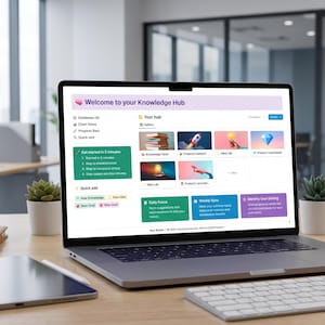 May include: A laptop displaying a webpage titled "Welcome to your Knowledge Hub" sits on a wooden desk. The screen shows various icons and text, including "Your Hub" and "Quick add." A notebook, pen, tablet, and keyboard are also on the desk, along with a small plant and a mug.