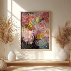 May include: An abstract floral painting in a wooden frame. The artwork features a vibrant mix of pink, yellow, and green brushstrokes, creating a textured and colorful display. The painting is a close-up of a bouquet of flowers.