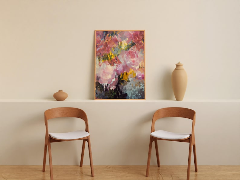 May include: An abstract floral art print in a wooden frame, featuring pink, yellow, and blue brushstrokes. Two wooden chairs with white seats are in front of a neutral wall. A vase and a decorative jar are on a shelf.