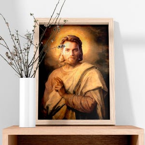 May include: Framed portrait of a man with long hair and a beard, wearing a light-colored robe, with a golden halo. The artwork is displayed on a wooden shelf next to a white vase with branches.