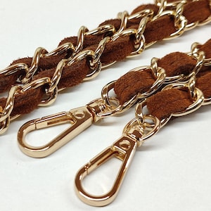 May include: A brown suede and gold chain handbag strap with two gold clasps.