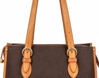 May include: A brown leather tote bag with tan leather trim and straps. The bag has a rectangular shape with a zipper closure and two top handles. Gold-colored metal hardware accents the bag, including buckles and a small ball charm.