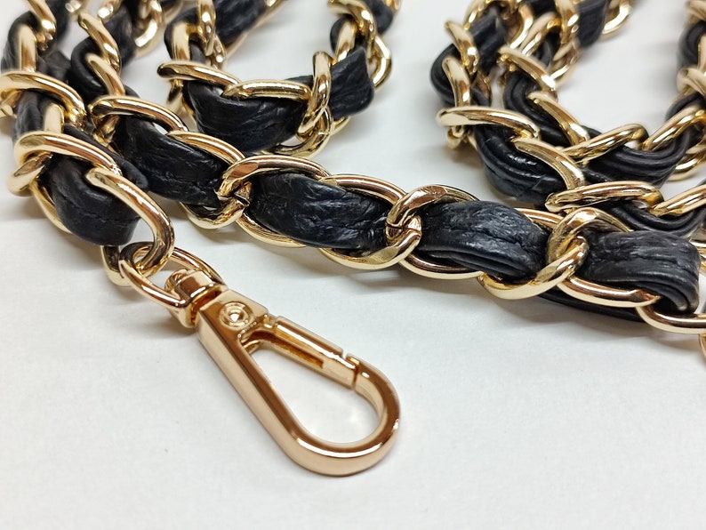 May include: A gold chain with black leather interwoven, ending with a gold clasp.