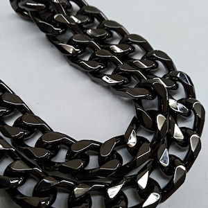 Peut inclure: Un collier cha&icirc;ne &eacute;pais noir avec un design &agrave; maillons plats. La cha&icirc;ne est en m&eacute;tal et a une finition brillante.