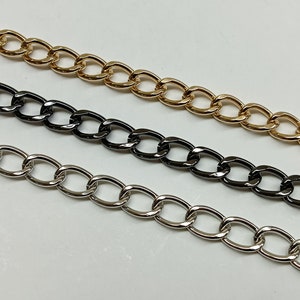 May include: Three chain links in different finishes: gold, black, and silver. The chains are all the same style, with oval links.
