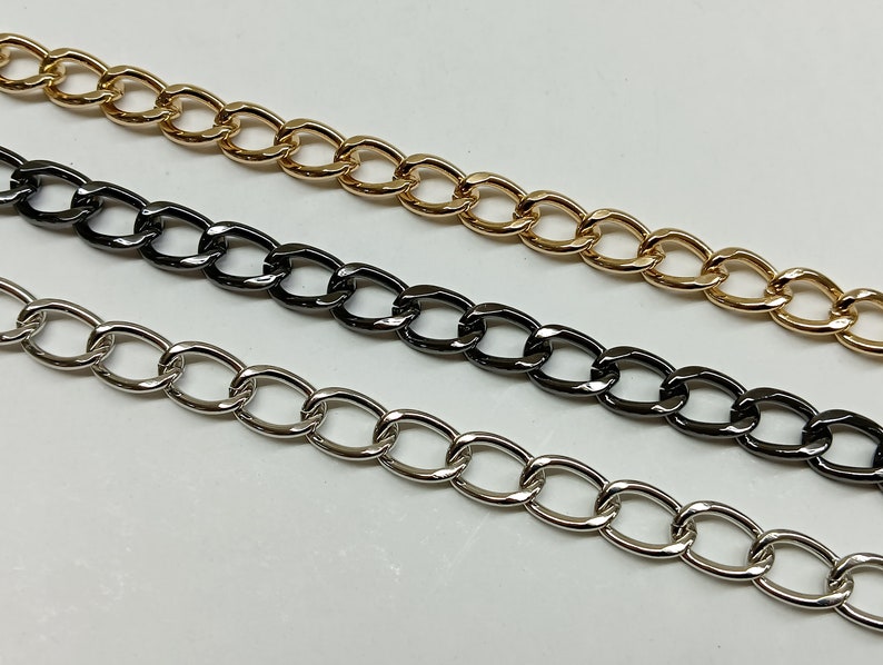 May include: Three chain links in different finishes: gold, black, and silver. The chains are all the same style, with oval links.