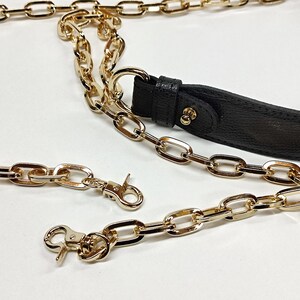May include: Gold-colored chain straps and a black leather strap. The chains have a lobster clasp closure. The chains are made of metal and have a shiny finish. The black strap has gold-colored hardware.