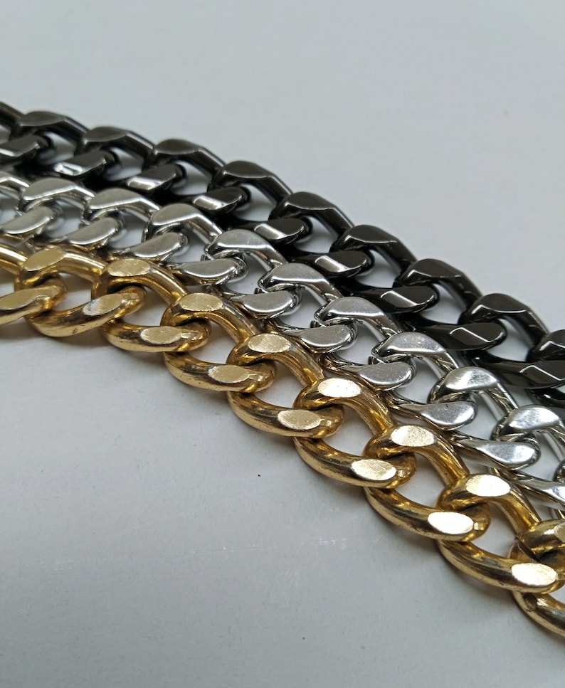 Peut inclure: Trois cha&icirc;nes curb en diff&eacute;rentes finitions&nbsp;: or, argent et noir. Les cha&icirc;nes sont dispos&eacute;es en rang&eacute;e, la cha&icirc;ne dor&eacute;e en bas et la cha&icirc;ne noire en haut.