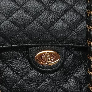 May include: A black quilted handbag with a gold chain strap and a gold clasp closure.