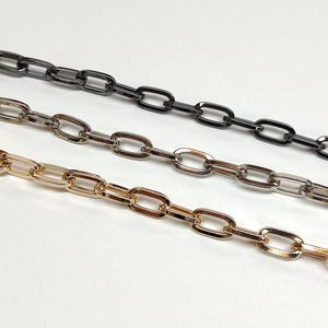 May include: Three metal chain strands in gold, silver, and black. Each chain has an oval link design. The chains are arranged diagonally against a white background, showcasing their color variations and link style.