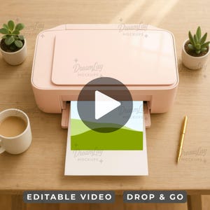 Könnte beinhalten: Ein hellrosa Drucker mit einem gedruckten Bild von grünen Hügeln und blauem Himmel. Der Drucker steht auf einer Holzoberfläche, mit einem goldenen Stift, einer Tasse Kaffee und zwei kleinen Topfpflanzen. Der Text "EDITABLE VIDEO" und "DROP & GO" sind sichtbar.