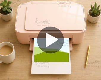 May include: A light pink printer with a printed image of green hills and a blue sky. The printer is on a wooden surface, with a gold pen, a cup of coffee, and two small potted plants. The text "EDITABLE VIDEO" and "DROP & GO" are visible.