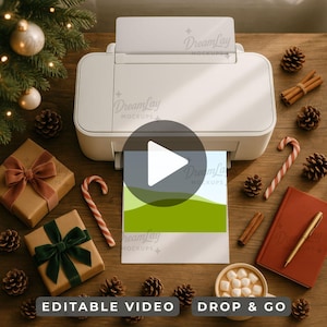 May include: A white printer printing a landscape image. The scene is set on a wooden surface with Christmas decorations, including pine cones, candy canes, and wrapped gifts. A mug of hot chocolate is also present.