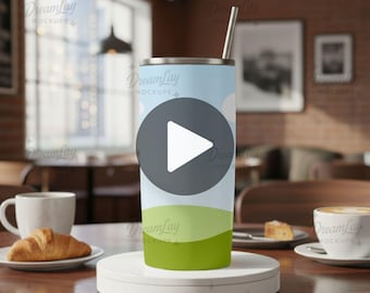 May include: A cylindrical tumbler with a landscape design featuring a blue sky, white clouds, and green hills. It has a silver straw and is displayed on a white platform. The words "EDITABLE VIDEO" and "DROP & GO" are at the bottom.