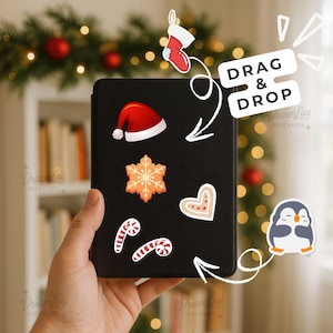 Könnte beinhalten: Ein schwarzes Tablet mit weihnachtlichen Aufklebern, darunter ein Weihnachtsmannhut, eine Schneeflocke, ein Herz, Zuckerstangen und ein Pinguin. Der Text "DRAG & DROP" ist ebenfalls vorhanden. Der Hintergrund zeigt eine Weihnachtsgirlande und ein Bücherregal.